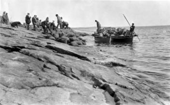 Raft with supplies pulling up to rocky shore, about 1925
