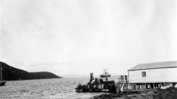 Storage shed and supplies on wharf, about 1925