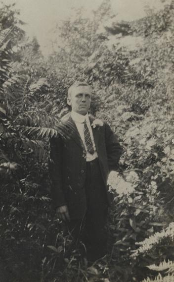 Man standing amongst shrubs and flowers, QC, ca. 1914