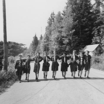 Guides walking hand-in-hand across a road, QC, 1962